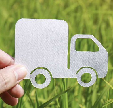 camion en papier blanc sur de la pelouse et tenu par un doigt